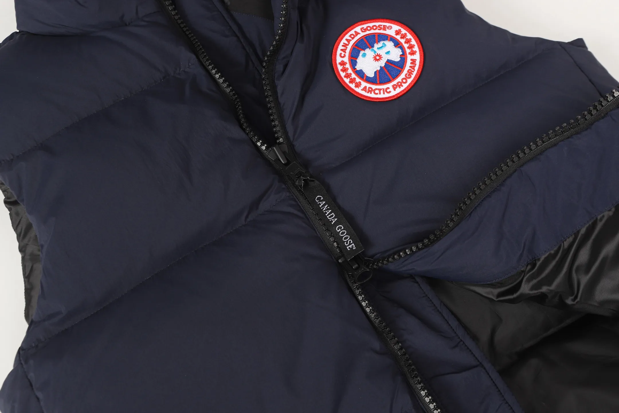 P560 Canada gooes Lawrence down vest (high version) The Lawrence down vest features a durable shell and quilted body, making it a must-have item for all seasons. The fabric has a durable soft touch. Longer hem at back for added protection. Reflective double-stripe grip tape at back. The Lawrence features an engineered down-filled collar to block strong winds, a two-way front zip and a longer rear hem.  Color: black with red label, black with black label, desert color, ocean blue Size: XS-2XL